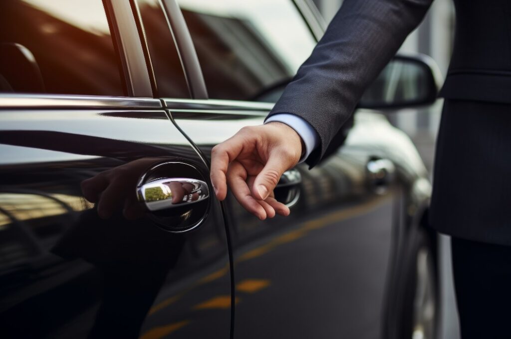 Die Hand eines Geschäftsmannes greift nach der Tür eines Luxusautos.