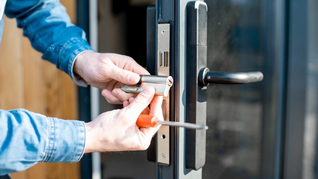 Ein Mann wechselt den Kern eines Türschlosses aus.